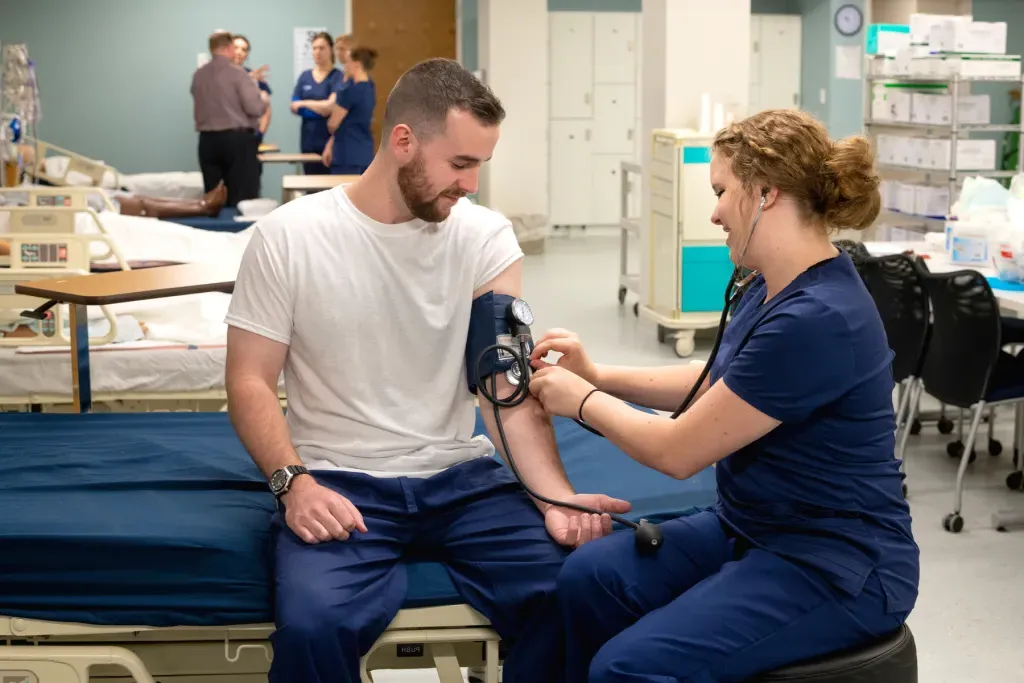 A nursing student takes another student's blood pressure in UNE's Interprofessional Simulation and Innovation Center