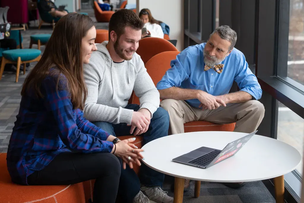 a faculty member sits with two students