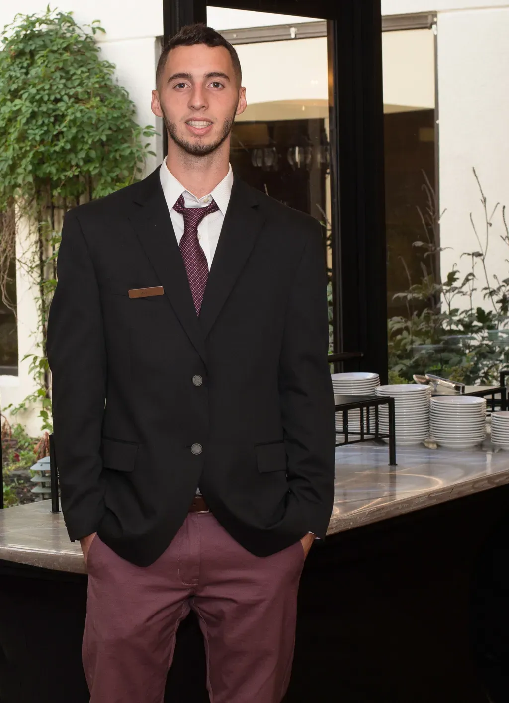 A U N E student stands in front of a table of plates and bowls at their hospitality internship