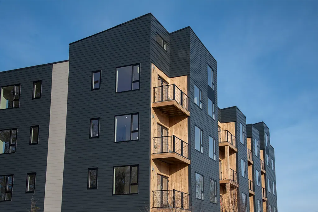 A blue-grey apartment building with wooden terraces 