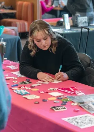 A volunteer stationed at a table during an organization fair in the Danielle N. Ripich Commons