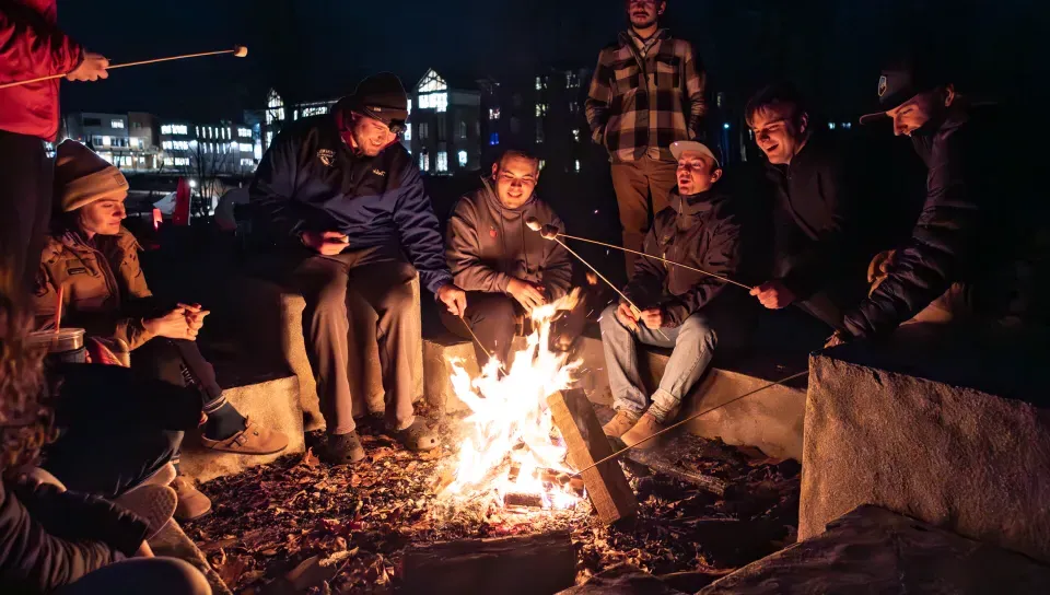 Students roast marshmallows over a bonfire at Jordan Point