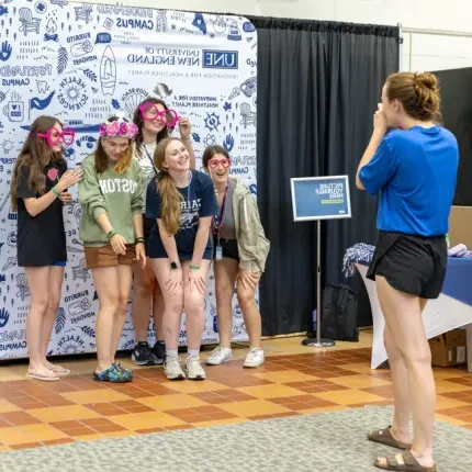 A group of students getting their photo taken in front of an illustrated background