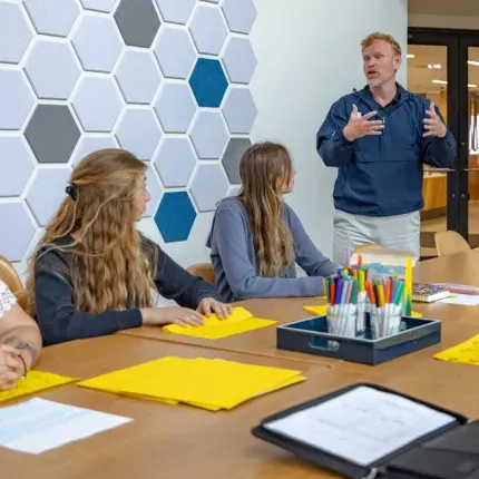 A professor talks to two students during a class