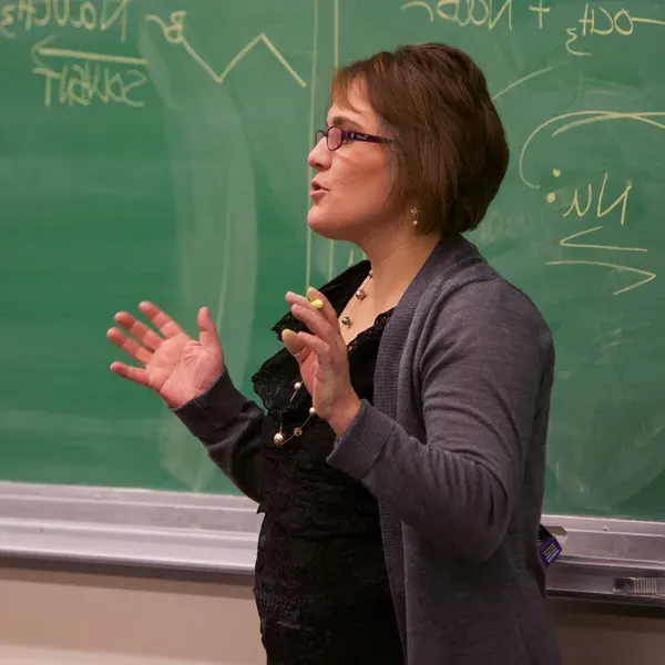 A faculty member stands in front of a chalkboard