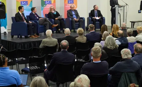 UNE President James Herbert introduces four panelists and a moderator onstage