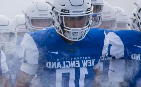 UNE football team members walk through the fog