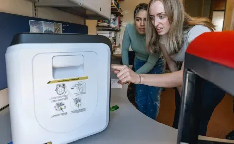 Two students operate a 3D printer