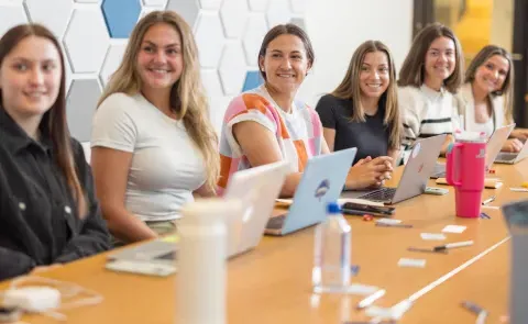 A group of UNE women business students sits around a conference table