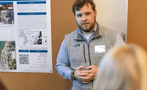 A UNE student presents his climate research to a group of conference attendees