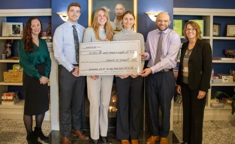 UNE medical students and local health leaders pose holding a large check in the amount of $1,600