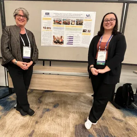 Photo of Emily Thomas and Kathryn Loukas posing in front of a research poster